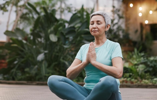 femme âgée en méditation les mains en prière vers le coeur