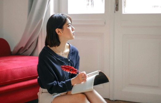 femme qui regarde par la fenêtre en tenant un journal dans la main