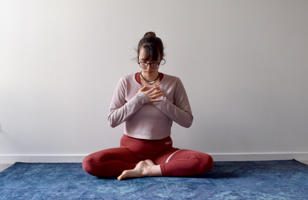 position assise, les mains jointes au coeur