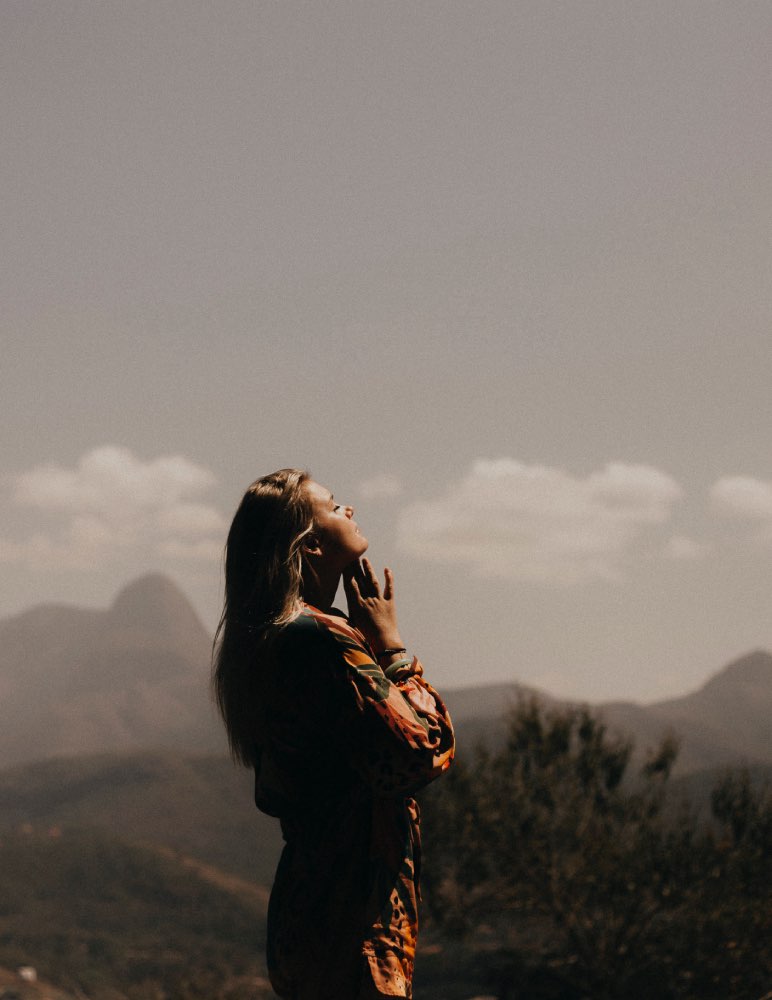 femme les mains en prière en pleine nature