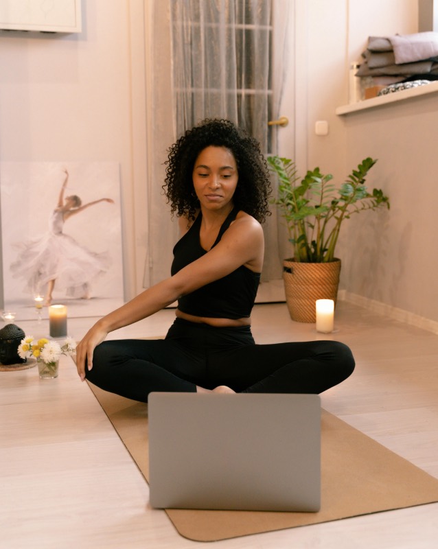 personne dans une position de yoga assise, suivant les directions sur un ordinateur