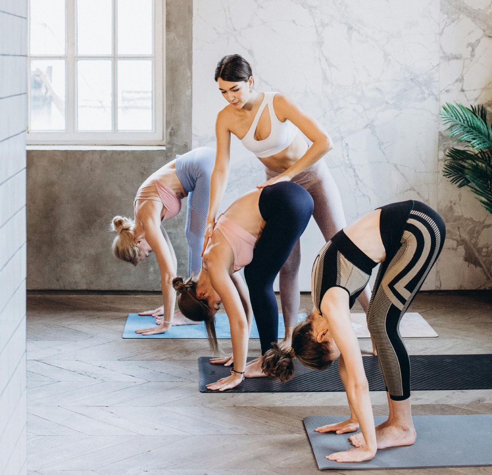 3 personnes dans la position de yoga de la pince debout